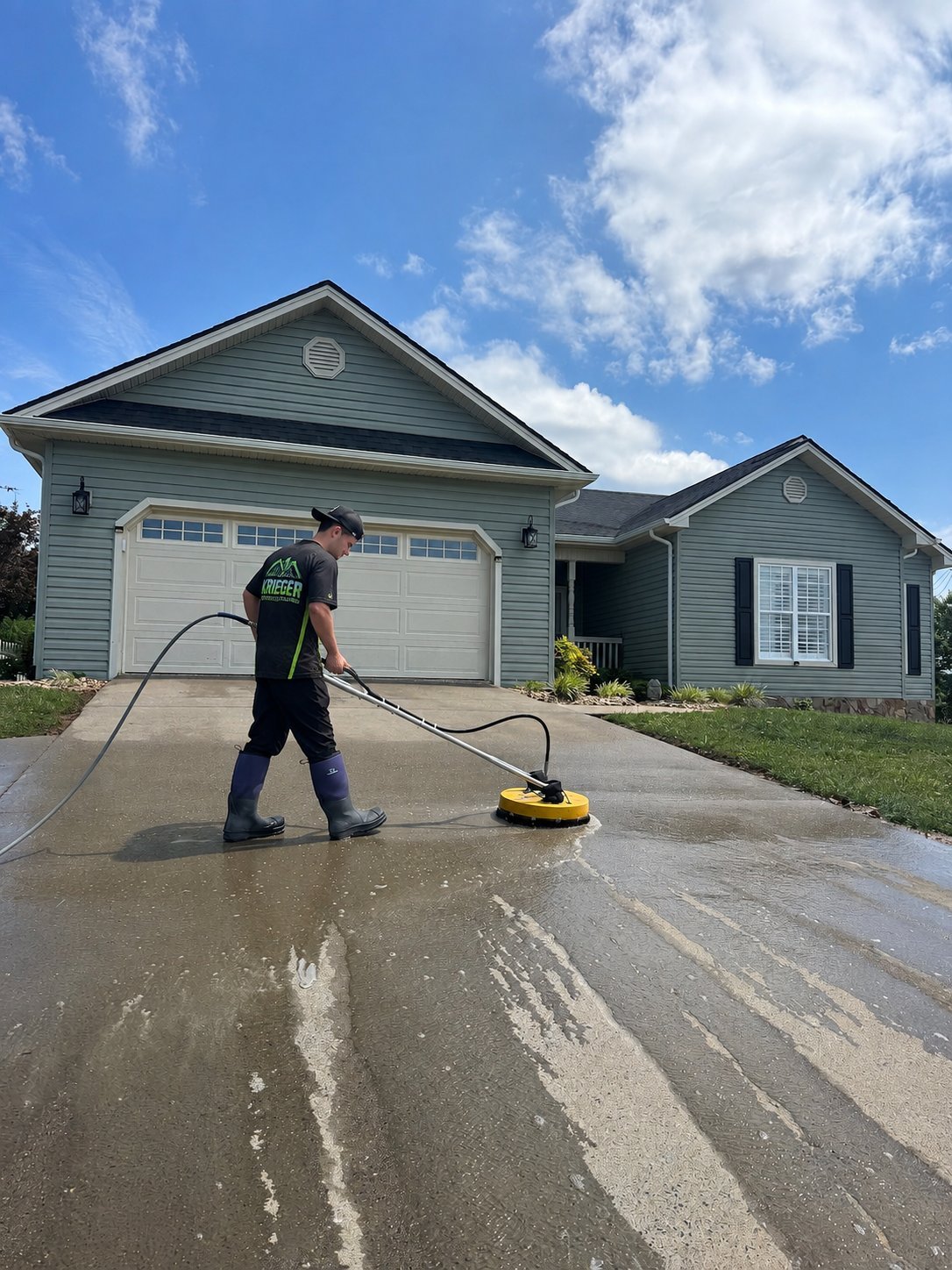 Krieger technician cleaning a residential driveway with a pressure washer